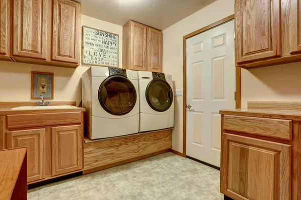 Laundry room with wooden cabinets and tile floor.