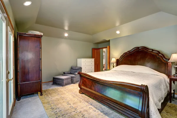 Bedroom interior with wooden king size bed and carpet floor.