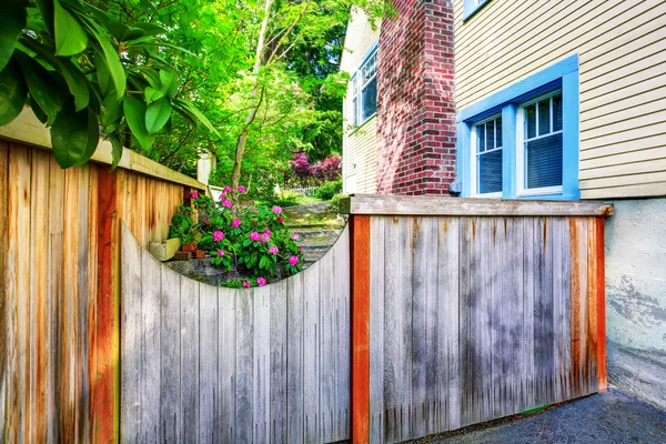 Wooden fence with gate to the backyard with side of the house.