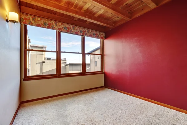 Empty room interior with wooden ceiling, red wall and carpet floor