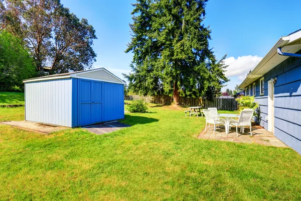 Spacious back yard of blue house with small shed