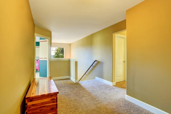Yellow hallway interior with beige carpet and wooden chest
