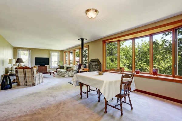 Traditional living room with tv set, carpet floor and many windows.