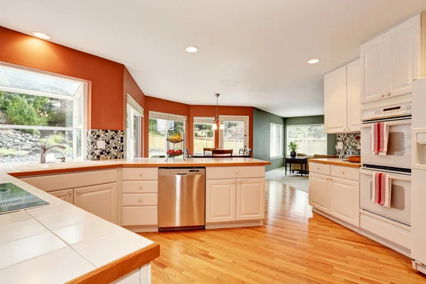 White kitchen room interior with tile counter top and hardwood floor.