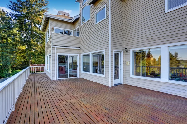 Two story house with wooden walkout deck overlooking backyard garden.
