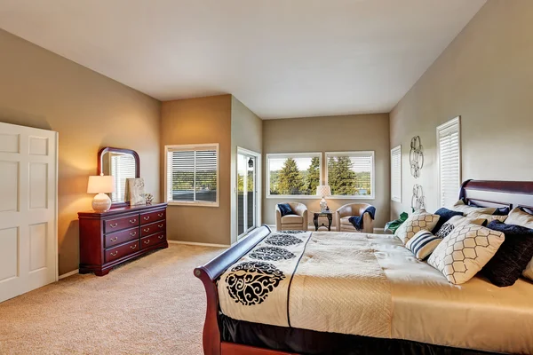 Spacious bedroom interior with beige walls and wooden furniture.