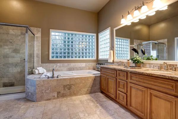 Luxury bathroom interior with vanity with granite counter top, large mirror and tile floor.