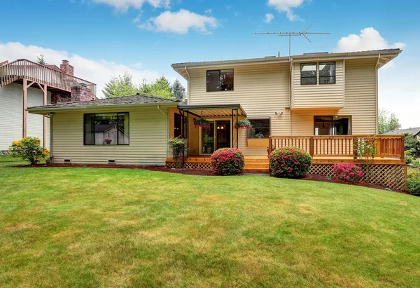 Wooden walkout deck. Well kept garden with bushes and flowers.