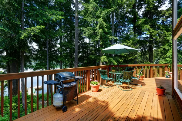 Balcony house exterior with patio area and opened green umbrella.