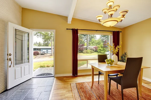 Dining room with table set, hardwood floor and red curtains.