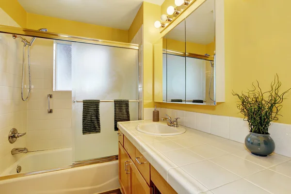 Bathroom interior in yellow tones and tile counter top.
