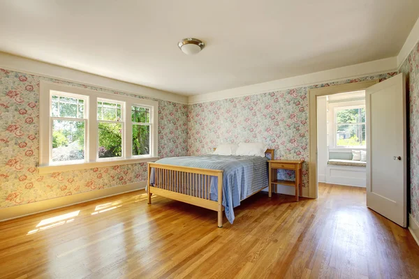 Bedroom interior with hardwood floor and vintage wallpaper walls.