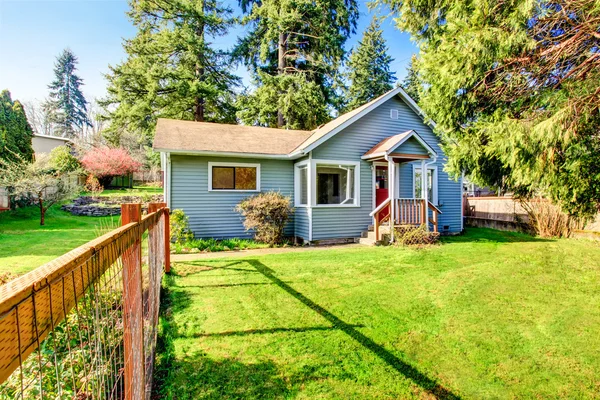 House with wooden deck. Front yard with flower bed and lawn