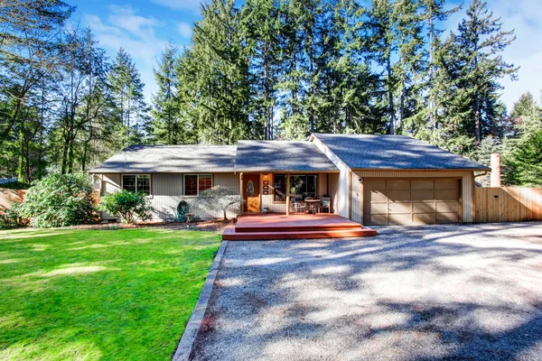 Grey house with wooden trim and gravel walkway. Curb appeal