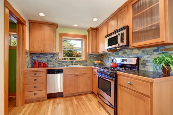 Light brown kitchen cabinetry and brick tile back splash trim