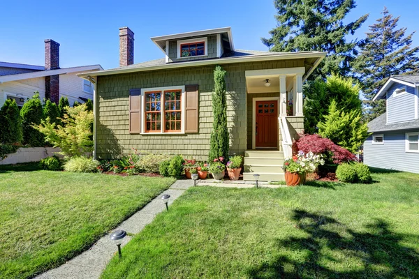 Small green American craftsman house exterior.