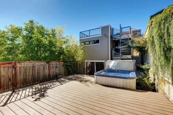 Small Wooden walkout deck with hot tub. House exterior.