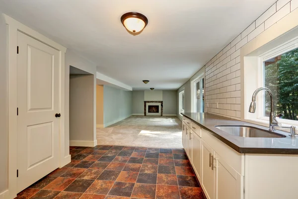 Empty room with a washbasin cabinet and brown tile floor.