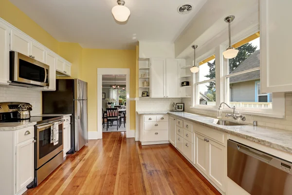 Kitchen interior with white cabinets, yellow walls and wood floor