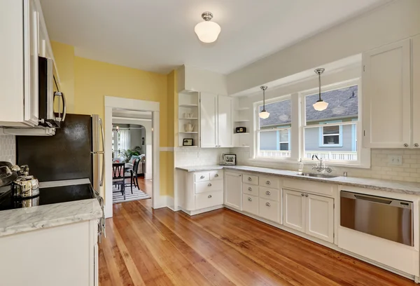 Kitchen interior with white cabinets, yellow walls and wood floor