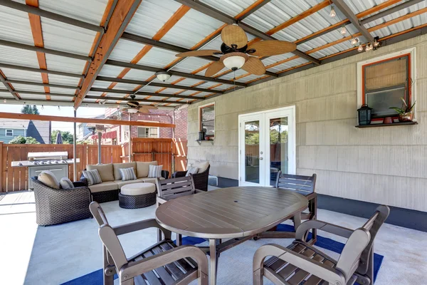 Covered back deck with concrete floor and outdoor furniture.