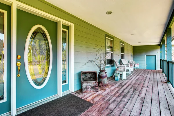 Large covered porch with white chairs and turquoise front door