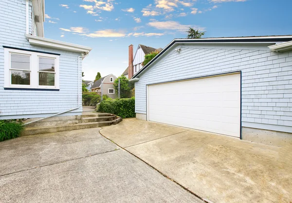 Separate garage with blue and white trim and driveway.