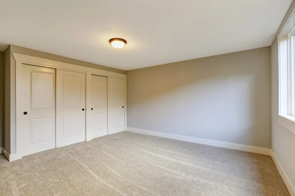 Empty room interior with blue tones walls and carpet floor.