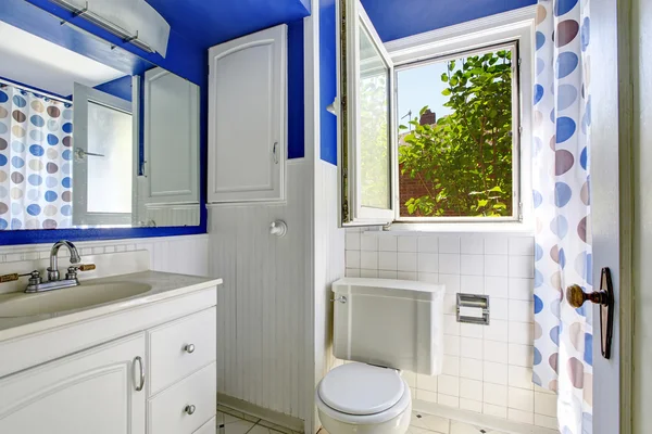 Bathroom interior in white and blue tones. White vanity cabinet and toilet