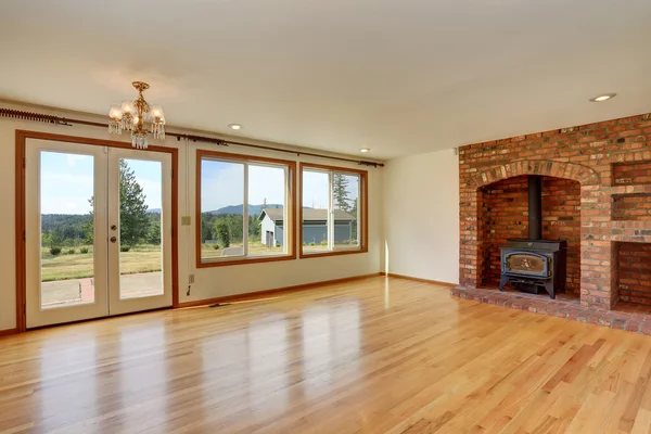 Empty living room interior in light tones with brick fireplace.