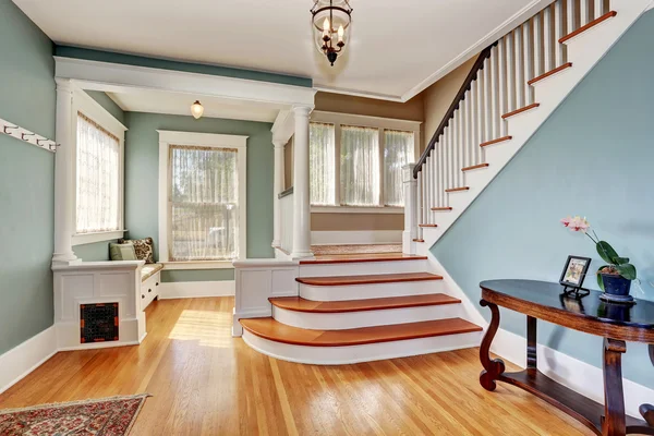 Hallway interior in blue tones, columns and hardwood floor. View of stairs.