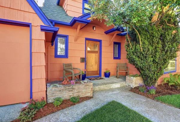 Coral exterior American house with blue trim. Concrete floor porch