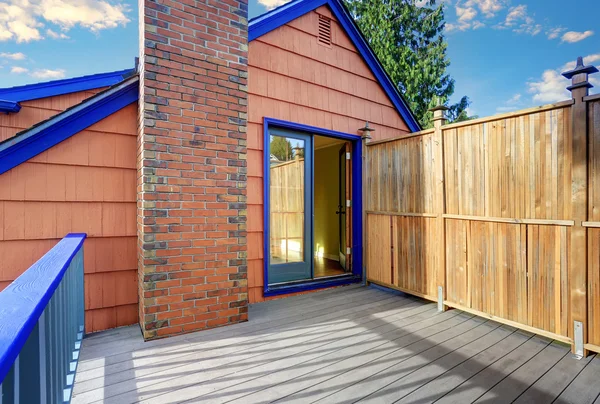 Wooden floor balcony of blue trim house in coral tones