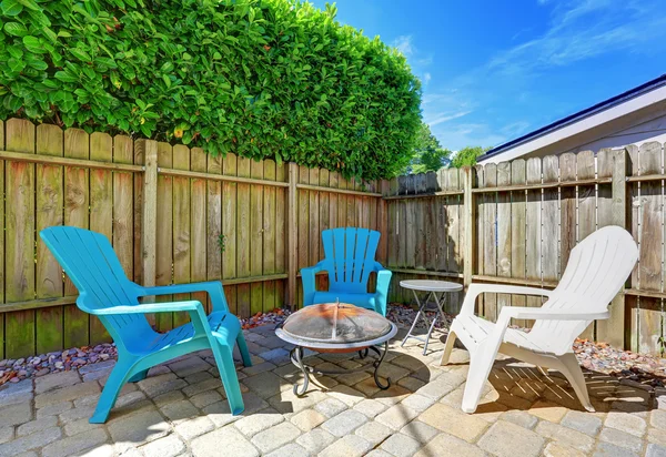 Fenced backyard with small patio area. Tile floor and green bushes