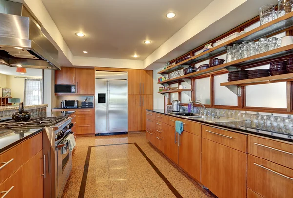 Kitchen interior with long wooden cabinets and shelves.
