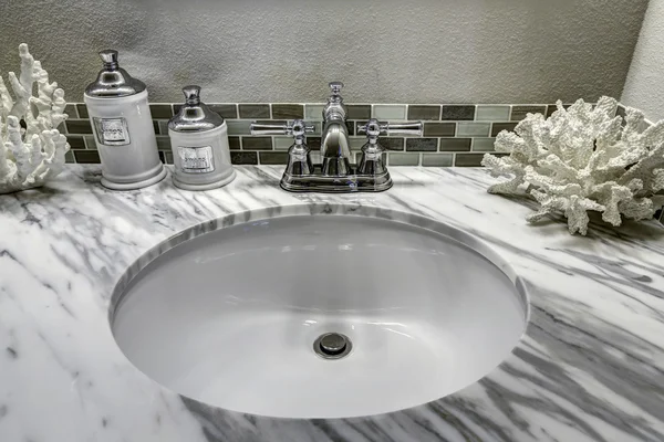 Bathroom vanity cabinet with white granite top. Sink and decorat