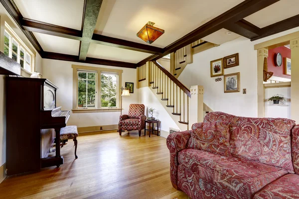 Family room with antique piano and comfortable red sofa