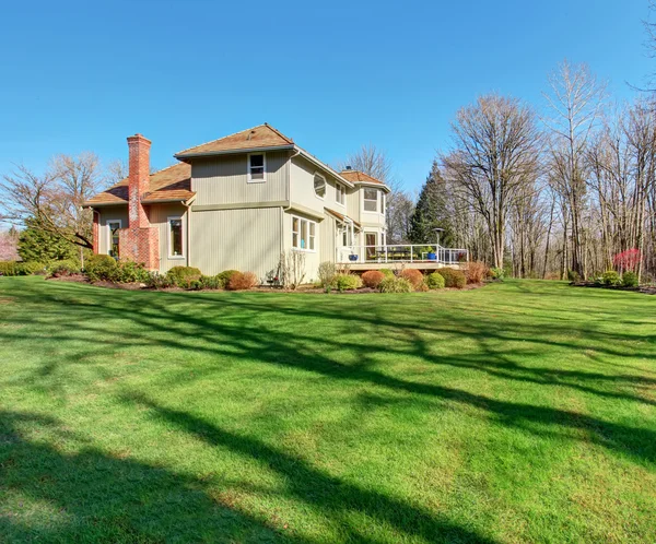 Large back yard with greenery, and furnished back porch.