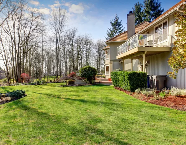 Large back yard with greenery, and furnished back porch.