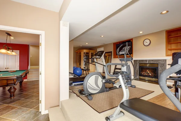 Home gym with TV and workout machines.