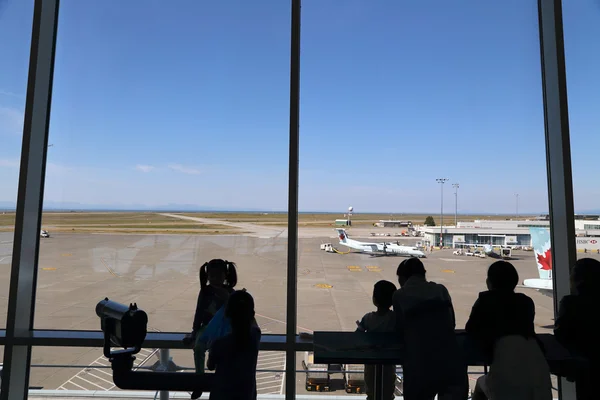 People inside YVR airport watching air canada airplane in Vancouver BC Canada.