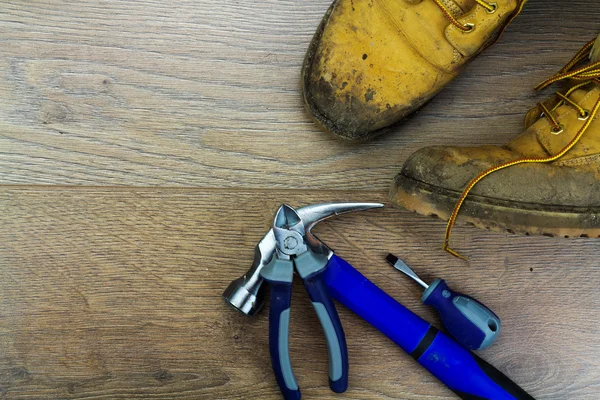 Muddy work boots and tools on a wooden floor