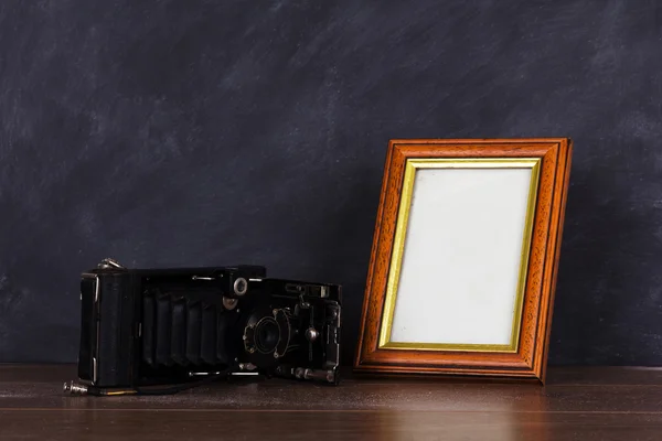 Vintage camera and frame against blackboard background