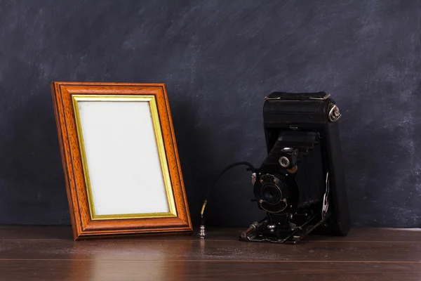 Vintage camera and frame against blackboard background