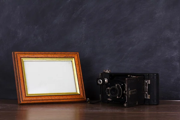 Vintage camera and frame against blackboard background
