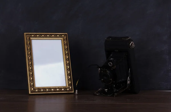 Vintage camera and frame against blackboard background