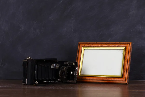 Vintage camera and frame against blackboard background