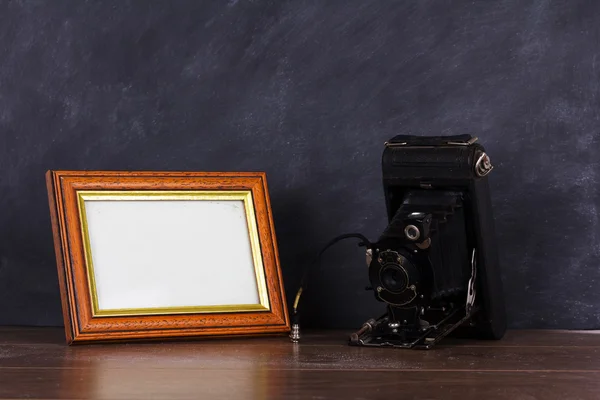 Vintage camera and frame against blackboard background