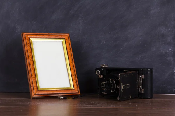 Vintage camera and frame against blackboard background