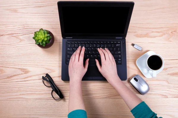 Office desktop setup with female hands working on laptop keyboar